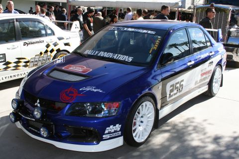 1998 Ford Crown Victoria - A blue Mitsubishi Lancer Evolution with racing decals and auxiliary lights is parked next to a white car.