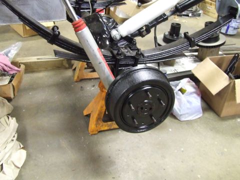 1967 Ford Bronco - A rear drum brake assembly, leaf springs, and shocks are shown supported by jack stands in a workshop setting.