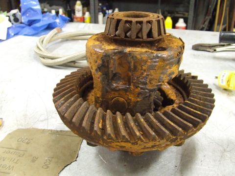 1967 Ford Bronco - A heavily rusted differential gear assembly sits on a workbench, with a bearing visible on top and sandpaper nearby.