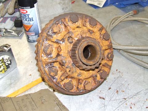 1967 Ford Bronco - Rusted differential carrier part on a workbench, next to sandpaper and a can of Krylon Rust Tough enamel.