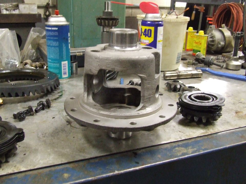 Differential carrier and gears on a workbench with spray cans and tools