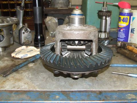 1967 Ford Bronco - A differential gear assembly is shown on a workbench, surrounded by various tools and automotive maintenance products.