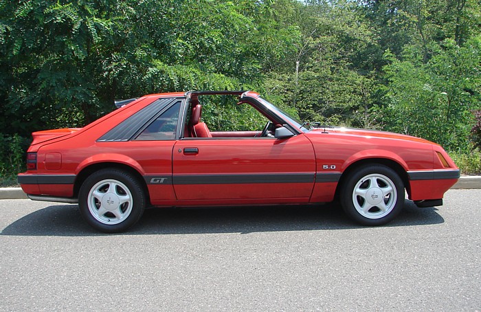Red convertible sports car with GT and 5.0 badges, louvers on rear window