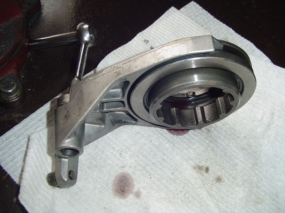 Clutch release fork with throwout bearing sitting on paper towels on a workbench