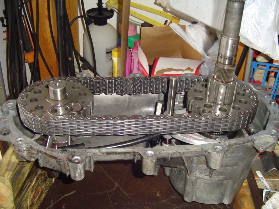 Opened transfer case showing drive chain, sprockets, and splined shaft on a garage workbench