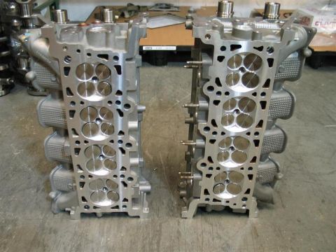 2007 Ford Mustang - A pair of engine cylinder heads are displayed in a workshop setting.