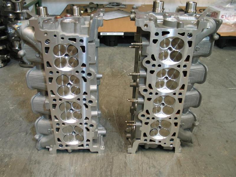 Two engine cylinder heads side-by-side in a workshop