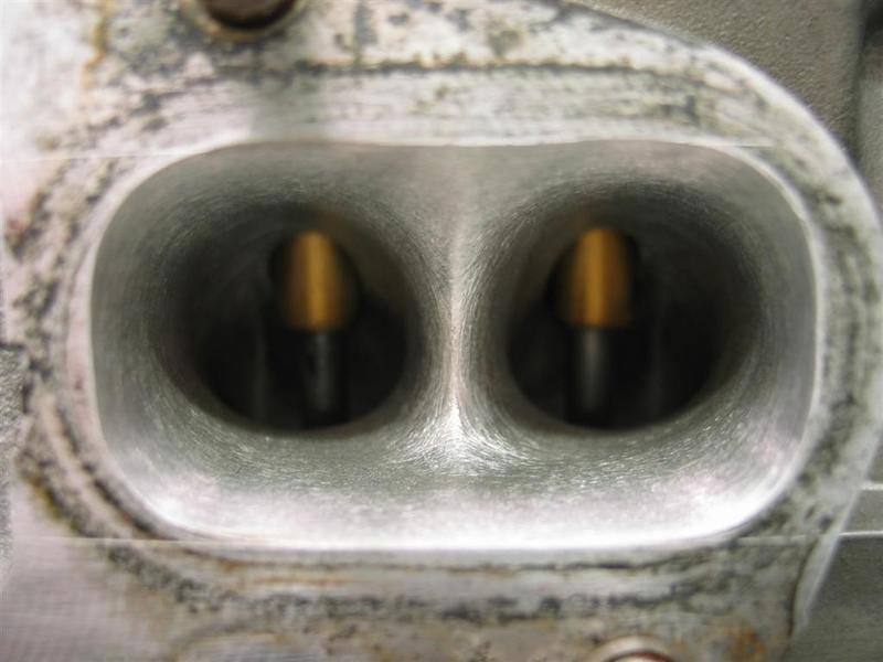 Close-up of two engine intake ports with yellow valve stems visible