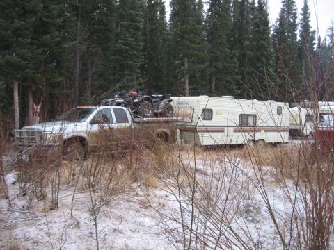 2005 Dodge 3500 - A silver pickup truck tows a travel trailer through a wooded area with snow on the ground.