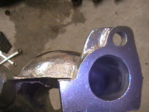 1990 Ford Probe - A close-up view of a metal exhaust manifold part, showing its construction and bolt holes.