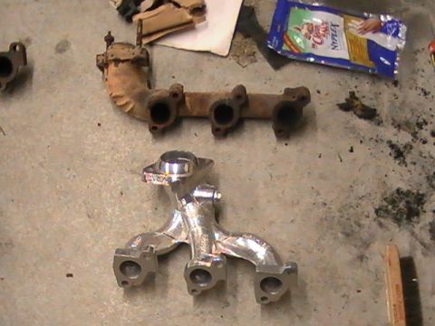 1990 Ford Probe - A comparison of old and new exhaust manifolds is shown on a workshop floor.