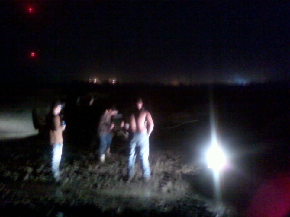 People stand in a dark field with a bright light source to the right