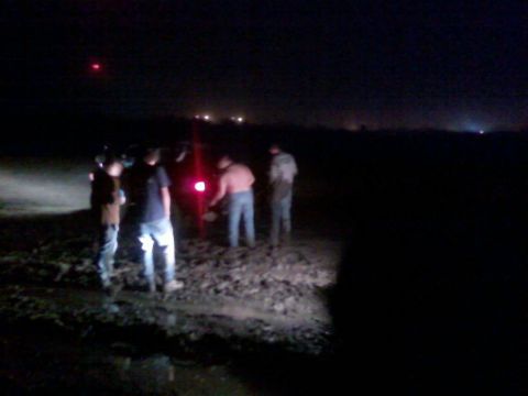 1996 Dodge 1500 - Several individuals are gathered in a dark, muddy area at night, illuminated by a red light source.