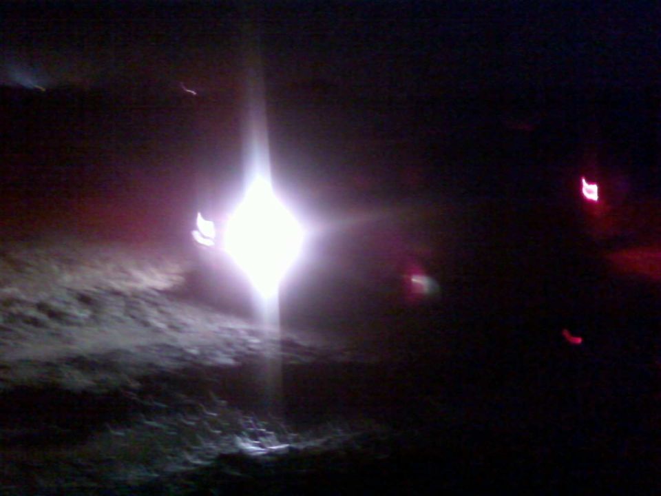 Headlights and taillights visible in the dark with a bright light source in the center