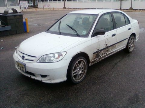 1996 Dodge 1500 - This white sedan has significant mud coverage on its lower body panels and doors.