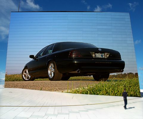 2003 Mercury Marauder - A black 2003 Mercury Marauder is reflected in a mirrored wall, showing its rear profile against a blue sky.