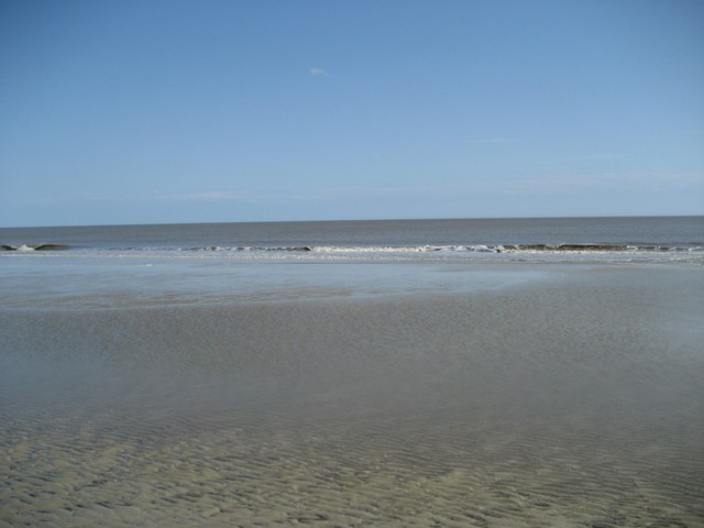 Beach with calm ocean and rippled sand at low tide