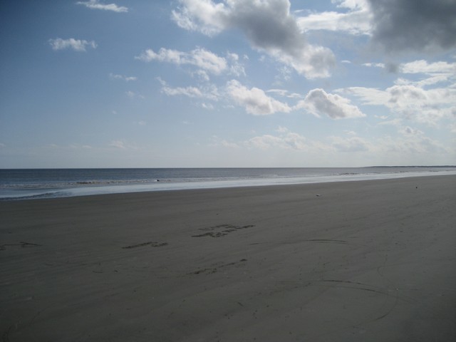 Wide beach with gentle waves under a cloudy sky