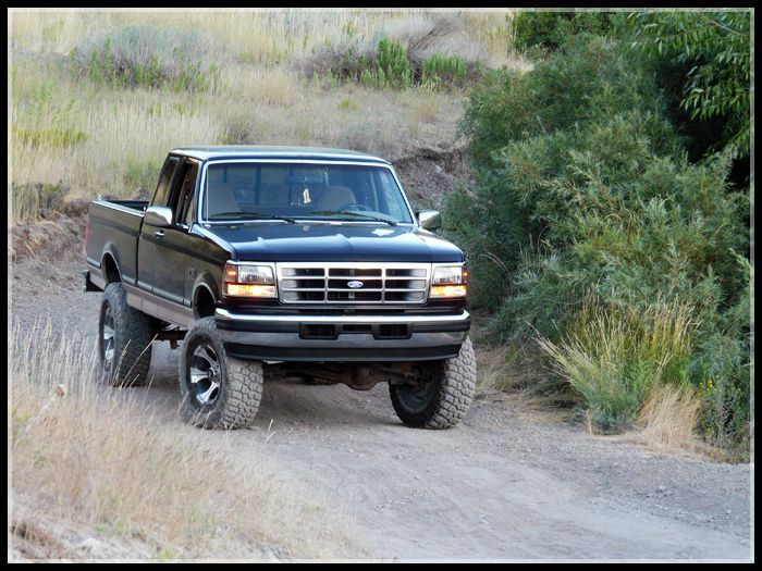 Black pickup truck with lifted suspension on a dirt road