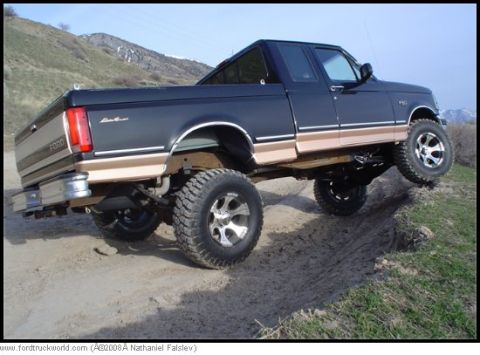 1996 Ford Bronco - This lifted 1996 Ford F-150 pickup truck is shown driving on a dirt path with one wheel off the ground.
