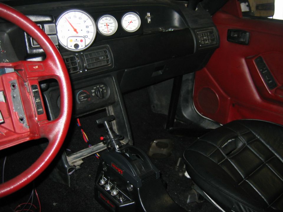 car interior, red steering wheel, aftermarket gauges, black racing shifter, red door panel