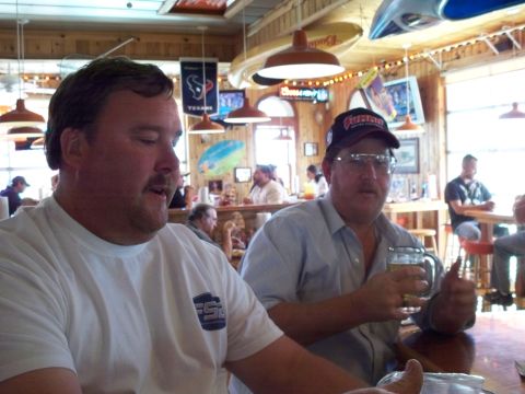 1996 Ford Bronco - Two men are seated at a table in a restaurant, with other patrons and decor visible in the background.