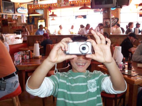 1996 Ford Bronco - A person holds a digital camera in front of their face inside a restaurant.