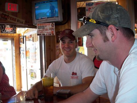 1996 Ford Bronco - Two men are seated at a bar in a Hooters restaurant, with a TV displaying a baseball game in the background.