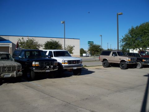 1996 Ford Bronco - Several Ford Broncos are parked in a lot under a clear blue sky.