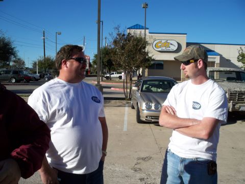 1996 Ford Bronco - Two men stand in a parking lot near a building with cars visible in the background.