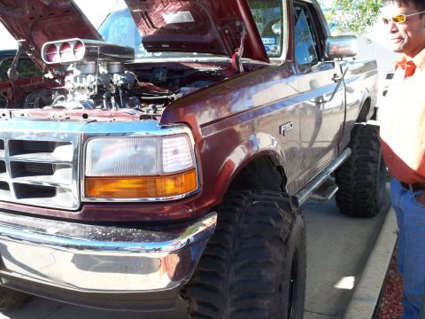 1996 Ford Bronco - A modified maroon Ford F-150 pickup truck is displayed with its hood open, revealing a powerful engine and custom modifications.
