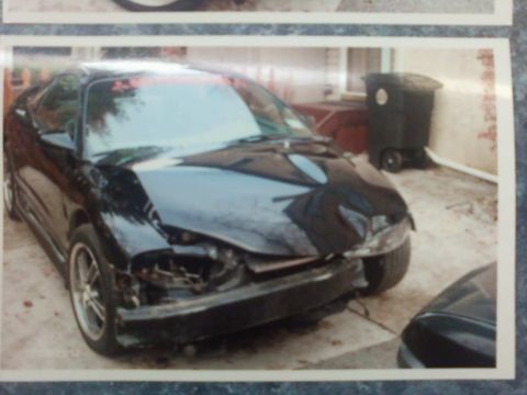 1996 Dodge 1500 - This black coupe has sustained significant damage to its front end, including a missing bumper and bent body panels.