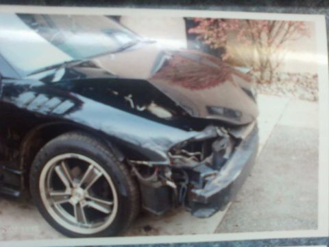1996 Dodge 1500 - The front end of a black car shows extensive damage, including a crumpled bumper and hood.