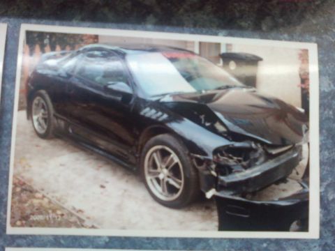 1996 Dodge 1500 - A damaged black coupe sits in a driveway, its front end severely compromised.