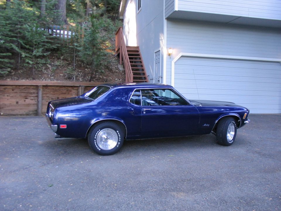 Blue coupe with vinyl roof and chrome wheels parked in a driveway