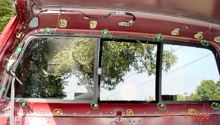 Red vehicle's rear window frame with visible bolts and wiring. Text reads OCT 4 2006