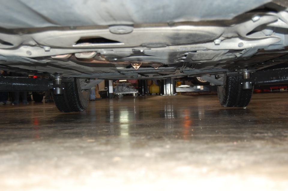 Underside view of a car on jack stands, showing tires and undercarriage