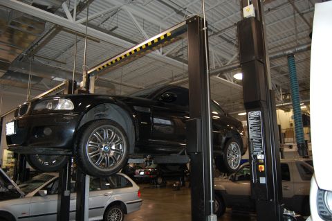 2002 BMW M3 - A black 2002 BMW M3 is raised on a hydraulic lift in a service bay.