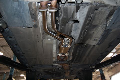 2002 BMW M3 - Underside view of a car's exhaust system and underbody components, likely in a repair shop.