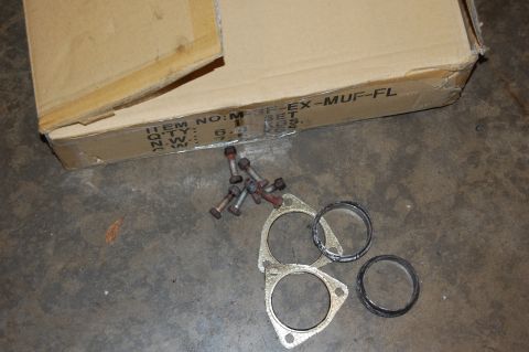 2002 BMW M3 - A set of exhaust gaskets and bolts are laid out on the floor next to a cardboard box with part information visible.