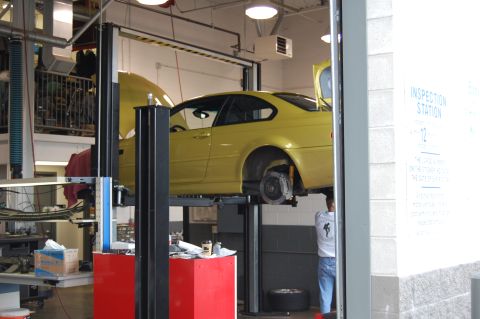 2002 BMW M3 - A yellow 2002 BMW M3 coupe is shown on a car lift in what appears to be a service bay.