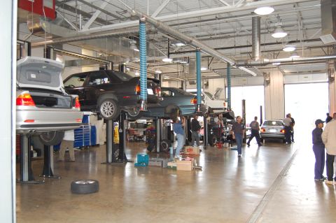 2002 BMW M3 - Multiple vehicles are undergoing service in a busy auto repair shop.