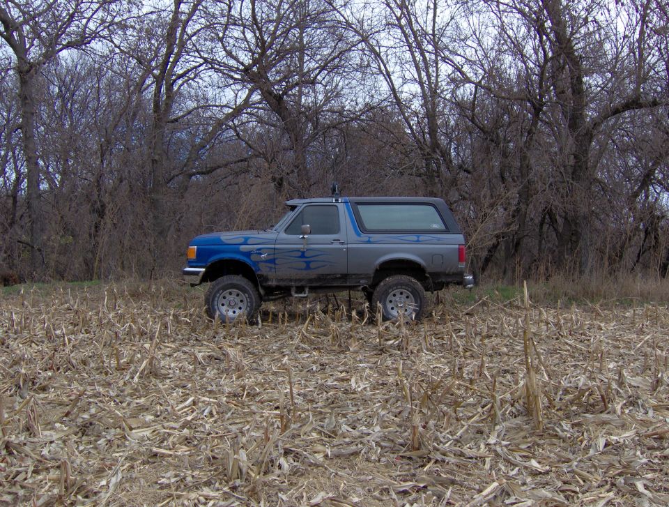 1987 Ford Bronco side view in a dry field with trees