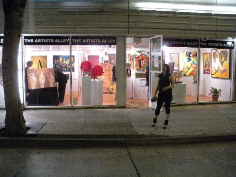 1989 Ford Bronco - The Artists Alley gallery displays various artworks through its large glass windows, with a woman standing outside.