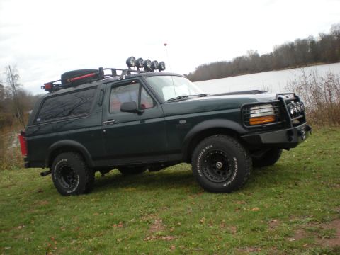 1993 Ford Bronco - This SUV, likely a 1992 model, is equipped for off-road adventures with a brush guard and roof-mounted lights.