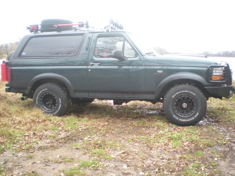 1993 Ford Bronco - This 1993 Ford Bronco is shown from the side, equipped with a roof rack and a spare tire mounted on top.