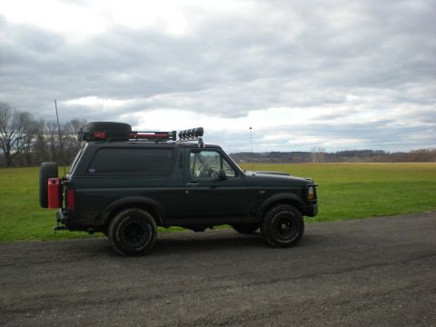 1993 Ford Bronco - This 1993 Ford Bronco is equipped with a roof rack and a rear-mounted spare tire, seen parked on a gravel road.