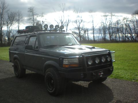 1993 Ford Bronco - Modified 1993 Ford Bronco parked outdoors with a cloudy sky overhead.