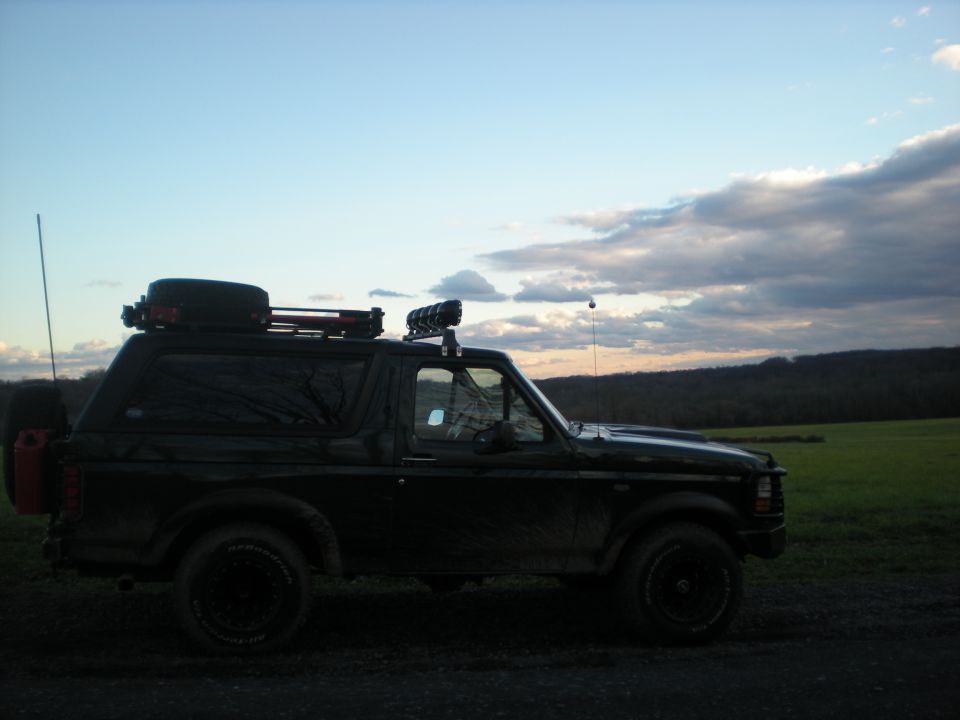 Black 1993 Ford Bronco with roof rack and spare tire on rear, parked outdoors.