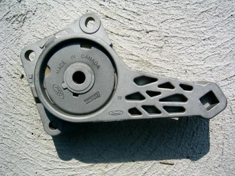 2007 Ford Mustang - Photograph of a cast Ford accessory-drive bracket or tensioner against a wall, a physical part not a document.
